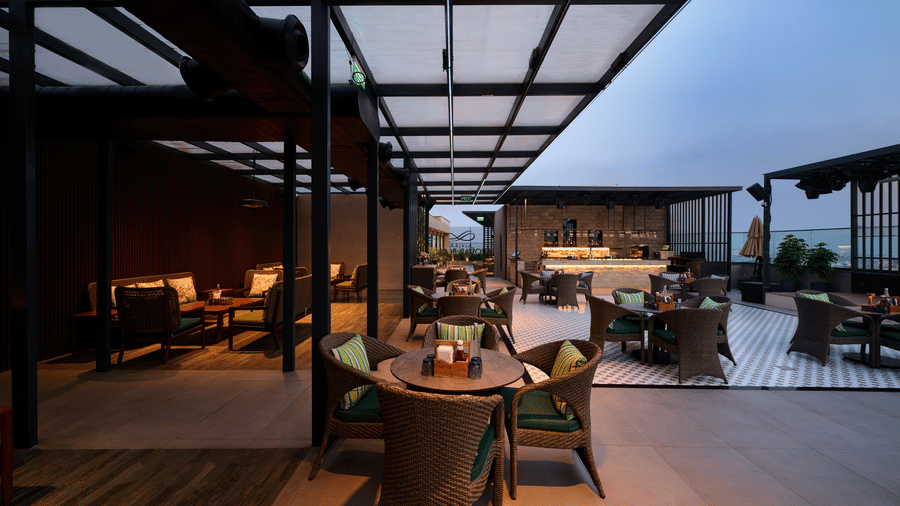 Covered rooftop dining area at Riviera Sarovar Portico, Pathankot with outdoor seating and a pleasant evening ambience.