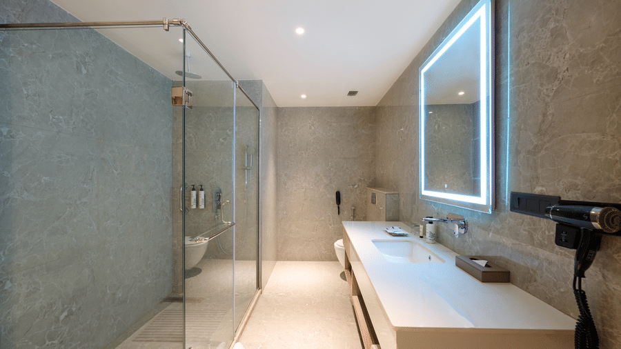 Modern bathroom at Riviera Sarovar Portico, Pathankot with glass shower enclosure, clean fittings and bright lighting.