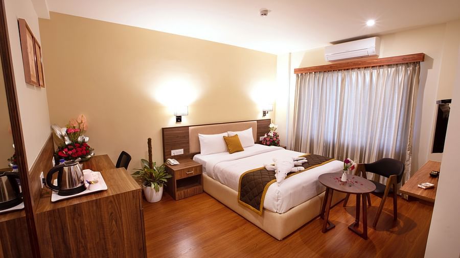 Wooden workstation with a tea/coffee setup, wall art, and a comfortable chair - RK Gardenia, Surya City.