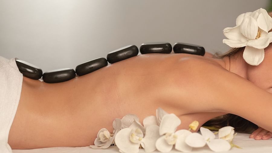 A woman sleeping on her stomach while getting a hot stone massage. 