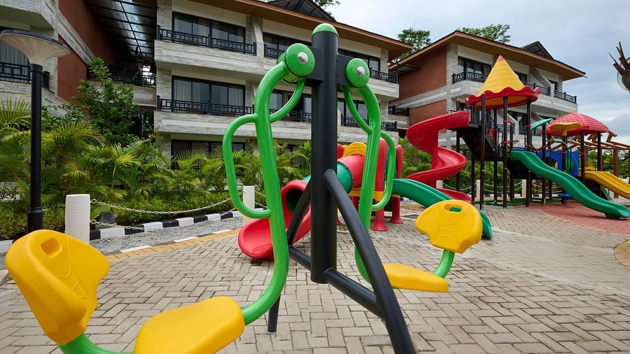 Outdoor playground with bright yellow and red swings and modern safety flooring - Royal Tulip, Chitwan