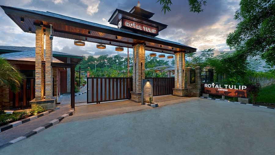 The hotel’s entrance lit up at night featuring a large archway, creating a warm and inviting ambience - Royal Tulip, Chitwan
