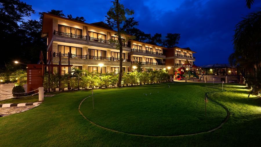 The hotel building lit up beautifully at night with a lush green lawn in front - Royal Tulip, Chitwan