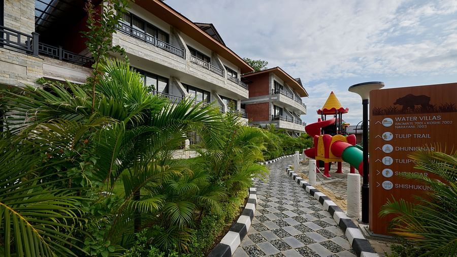 A pathway leading to the hotel entrance lined with plants and signage - Royal Tulip, Chitwan