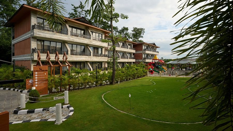 A multi-storey hotel building featuring a lush green lawn in front - Royal Tulip, Chitwan