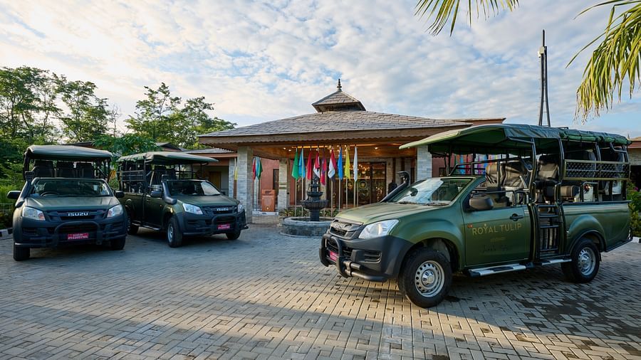Safari jeeps lined up outside the hotel with a well-maintained parking area featuring palm trees - Royal Tulip, Chitwan