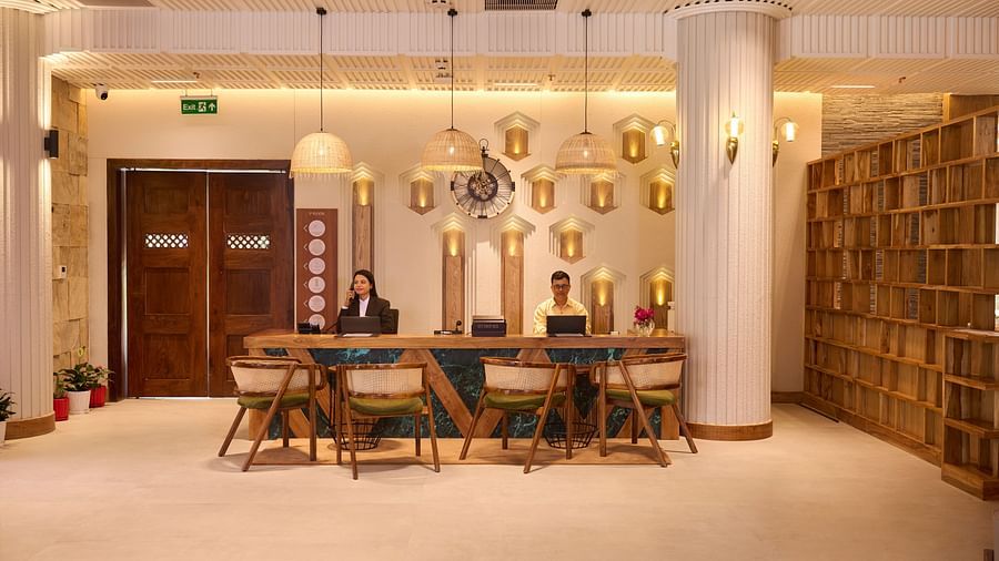 A reception area featuring receptionists, wooden decor, a urli bowl, and warm lighting - Royal Tulip, Chitwan