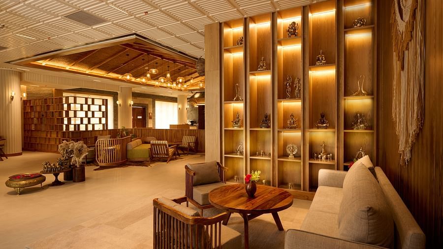 A wide angle shot of a lobby with cosy seating area, warm lighting and modern decor with wood furnishings - Royal Tulip, Chitwan
