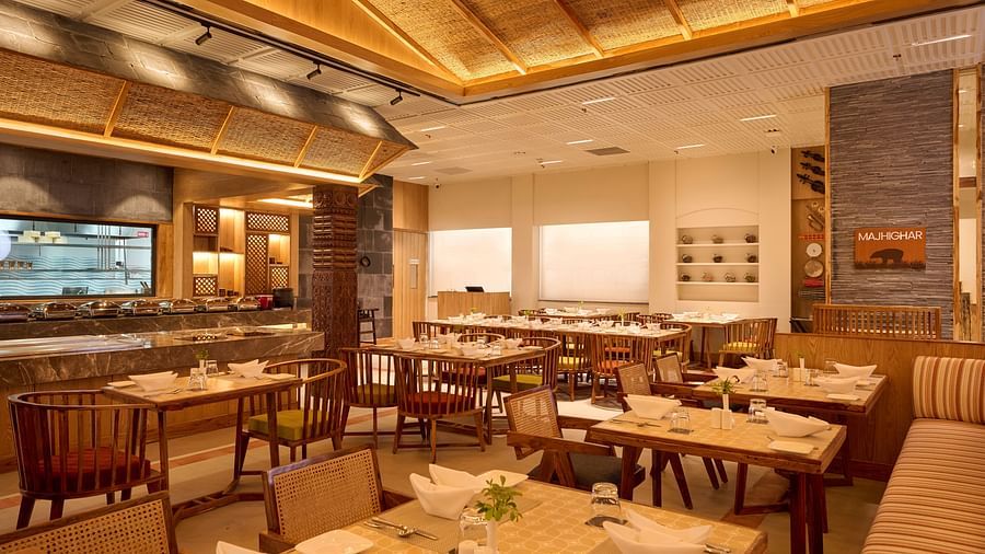 A dining area with wooden interiors, a live counter, and neatly arranged tables - Royal Tulip, Chitwan