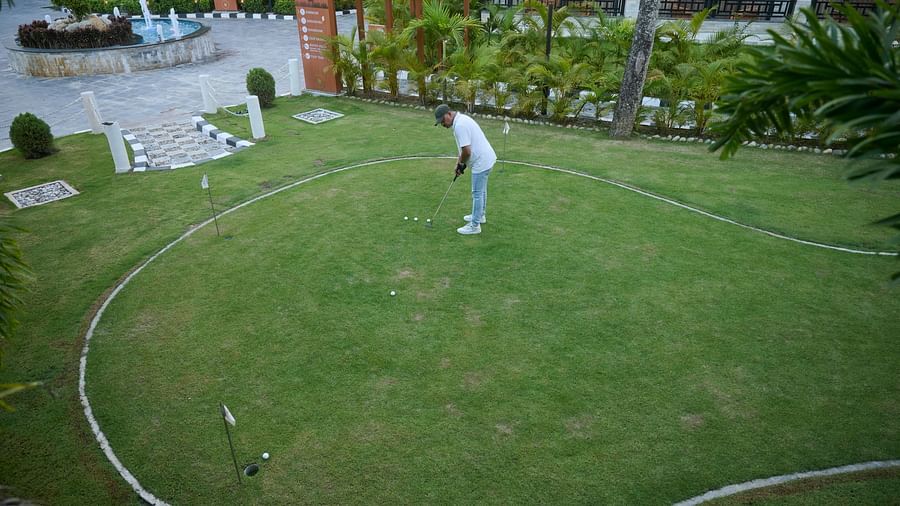 A man dressed in white enjoying mini golf surrounded by landscaped garden - Royal Tulip, Chitwan