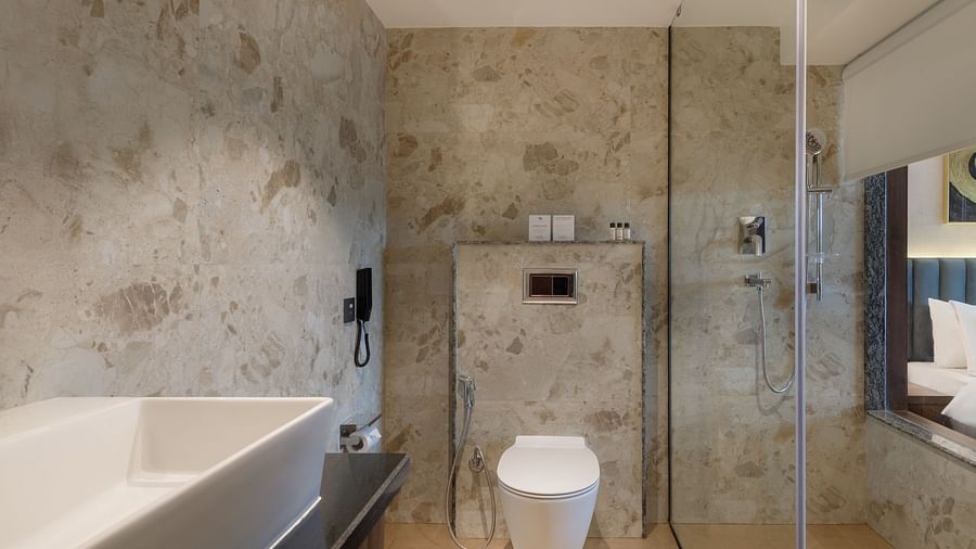 A modern bathroom at Royal Tulip, Kathmandu, with a white basin, toilet, and glass shower enclosure.