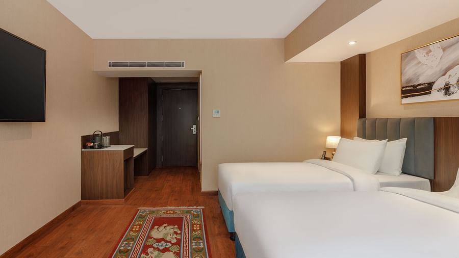 Twin beds in a comfortable room at Royal Tulip, Kathmandu, with a television and work area.