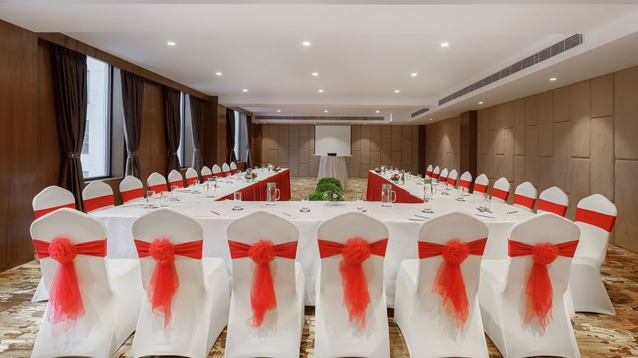 A meeting room at Royal Tulip, Kathmandu, set up in a hollow square with chairs featuring red sashes.