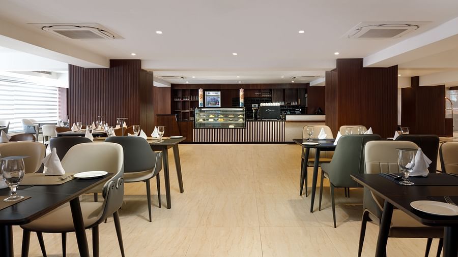 The dining area at Royal Tulip, Kathmandu, with tables set and the pastry counter visible in the background.