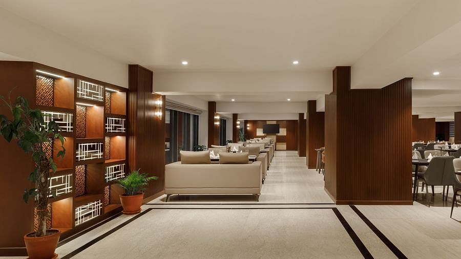 A long, inviting lounge at Royal Tulip, Kathmandu, with comfortable seating and decorative shelving.