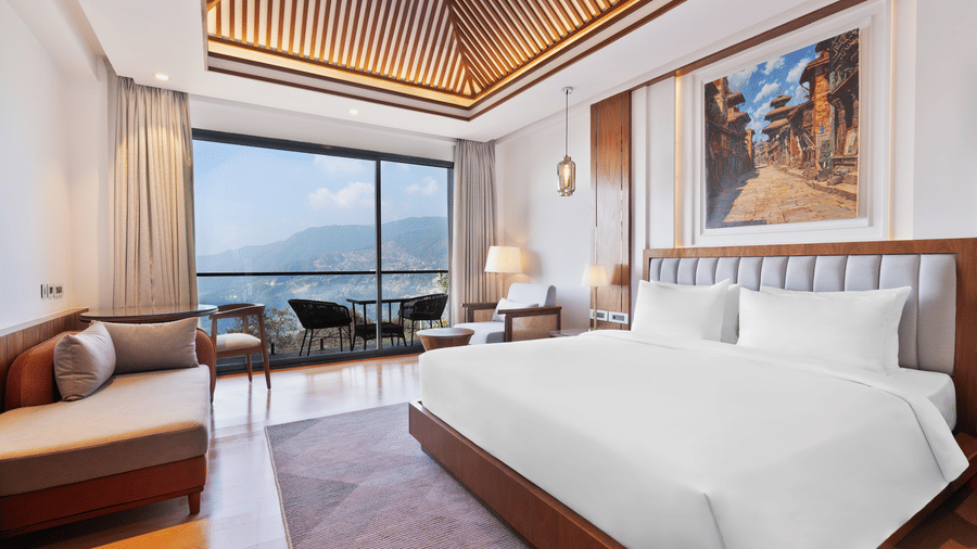 Premium Room bedroom at Royal Tulip Shivapuri National Park - Kathmandu featuring a king bed, a sofa, and a balcony with a view of the mountains.