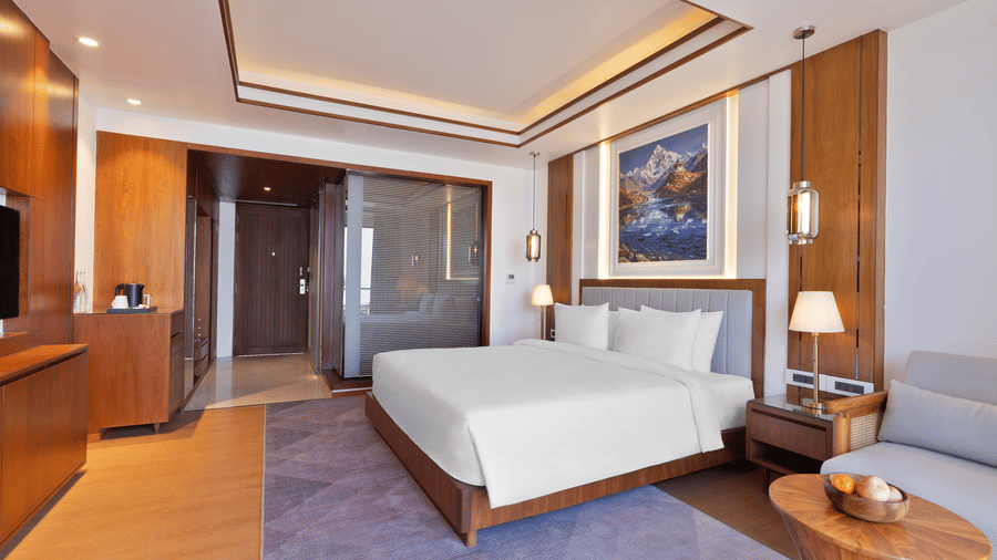 Modern Premium Double Room at Royal Tulip Shivapuri National Park - Kathmandu with wood furniture, a plush bed, and a sleek glass-partitioned bathroom.