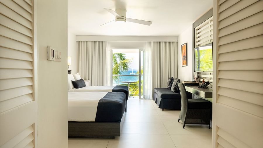 An image of a hotel room with double beds, a wall-mounted television and a balcony offering beautiful views - S Hotel Montego Bay, Jamaica