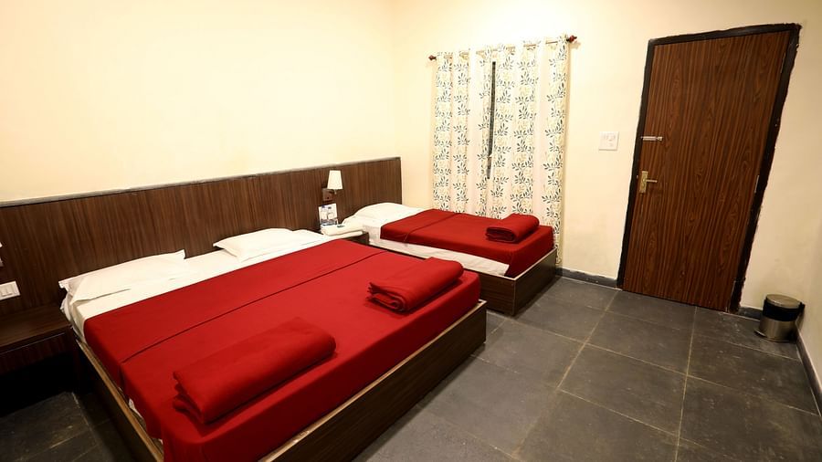 Warli Hut Interior - Sajan- one double bed and one single bed with white linens and red blankets.