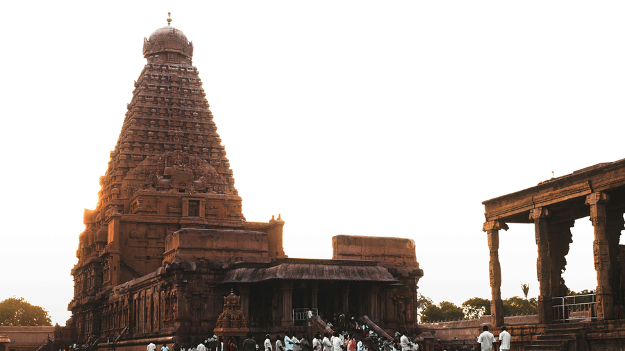 The historic Brihadeeswara Temple in Thanjavur, featuring its massive stone Vimana tower under a bright, hazy sky. It is one of the popular places to visit in Thanjavur for it's architecture.