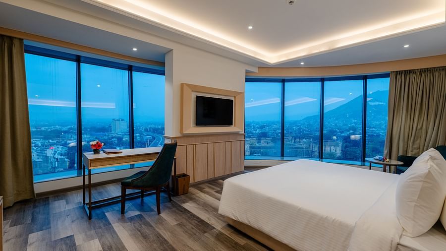 A hotel room in ajmer with a king size bed, a writing desk, a television, and panoramic view of the city - Sarovar Portico, Ajmer
