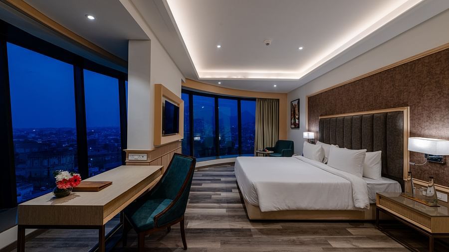 A hotel room in ajmer featuring wooden ascents, a king size bed, ambient lighting and views of the city - Sarovar Portico, Ajmer