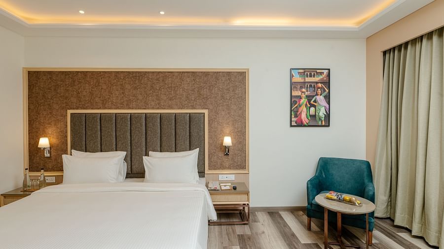 A hotel room with a king size bed, night stand, a couch and a teapoy - Sarovar Portico, Ajmer