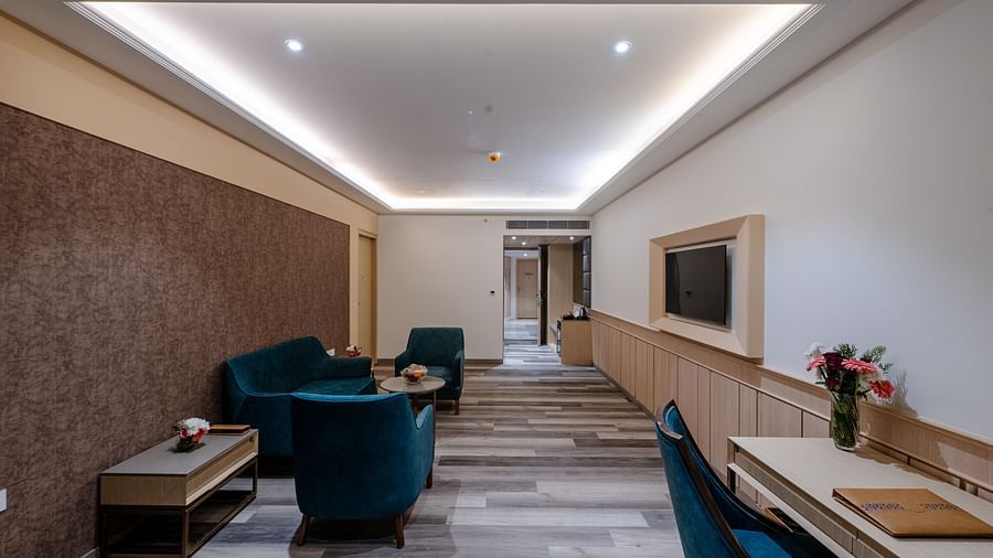 A seating area featuring a wall mounted television, a sofa set and a writing desk  - Sarovar Portico, Ajmer