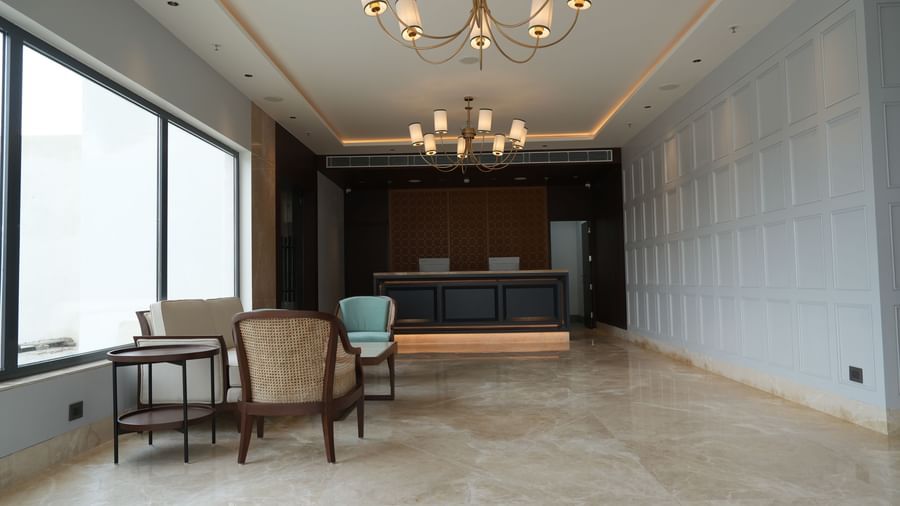 A hotel reception area showcases a dark wood reception desk with a light-coloured countertop and a modern design | Sarovar Portico, Hanumangarh