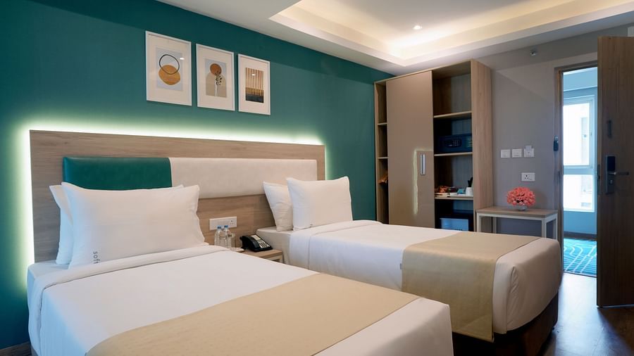 twin beds, artwork on the wall, a wardrobe with an in-room safe, snacks, and a minibar inside one of the executive rooms at Sarovar Portico, Kolkata Rajarhat