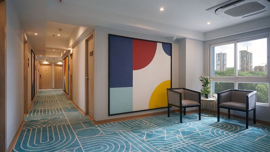 artwork and chairs beside a window in a corridor at Sarovar Portico, Kolkata Rajarhat