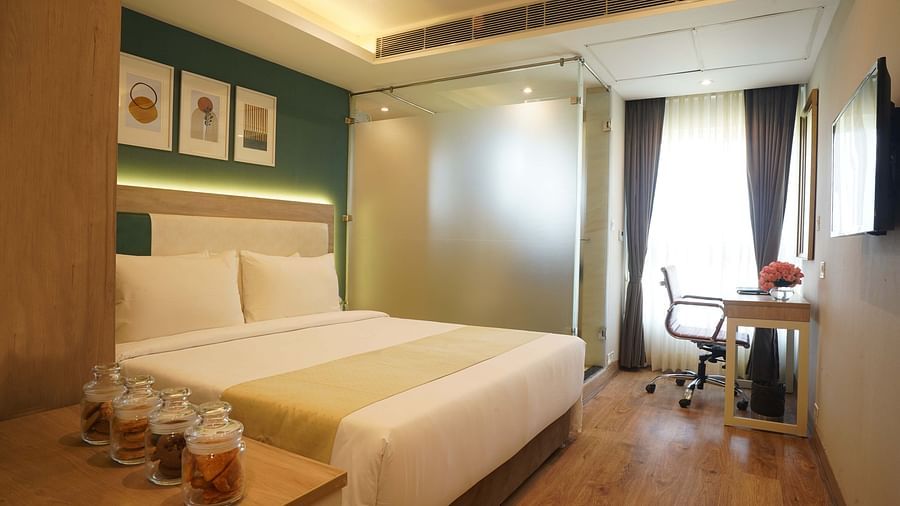 view of the double bed, side table, television, and the work desk and chair in one of the standard rooms at Sarovar Portico, Kolkata Rajarhat