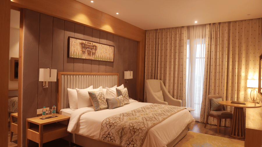 Guest room at Sarovar Portico, Somnath with a bed, side tables, wall art, curtains, and soft lighting.