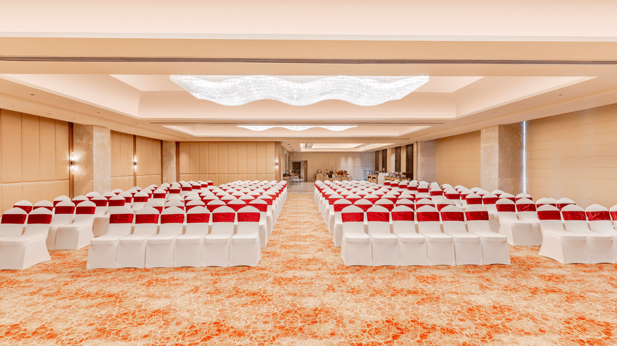 A banquet hall at Sarovar Premiere Alwar with rows of chairs and a patterned carpet on the floor.