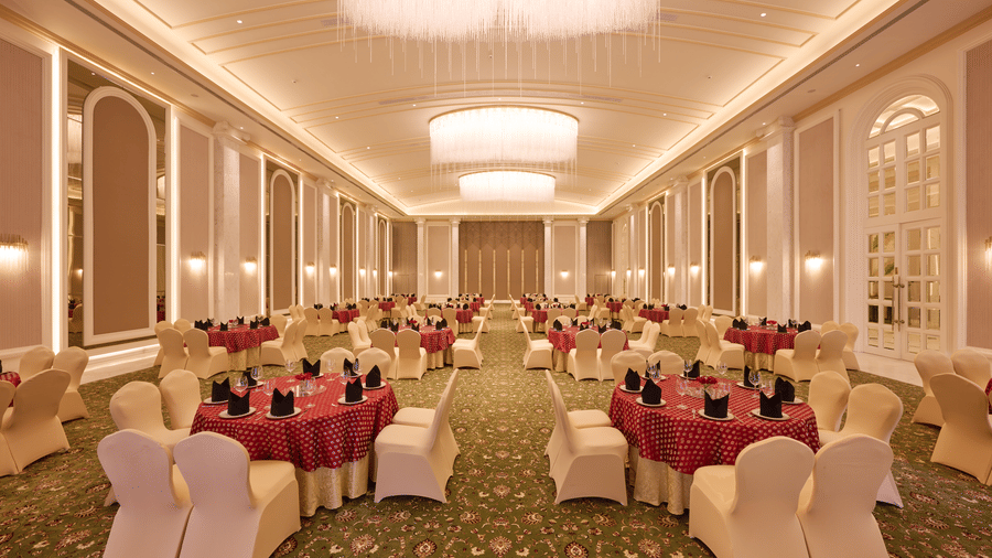 Banquet hall with round tables, chairs, and ceiling lights at Sarovar Premiere Amritsar.