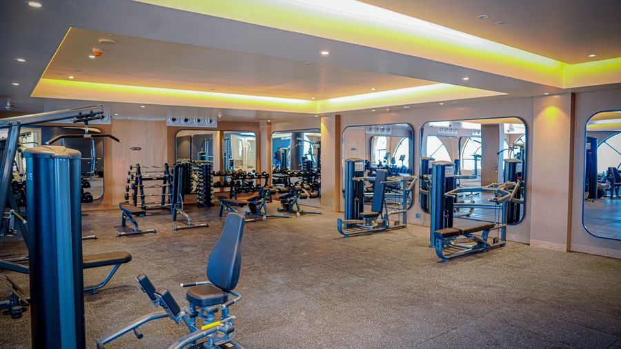 A modern fitness centre in Hargeisa featuring cardio and weight training equipment and large mirrors - Serene Sarovar Premiere Hargeisa