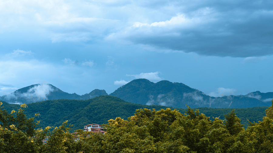 Expansive view of green hills under a moody blue sky with scattered clouds