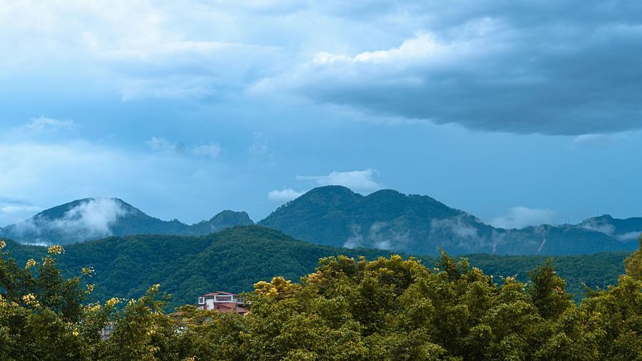 Expansive view of green hills under a moody blue sky with scattered clouds.