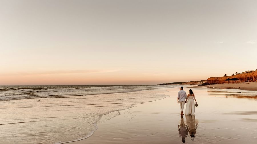 a couple walking on the beach with waves overlapping on the beach
