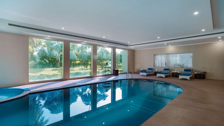 Relaxing swimming pool surrounded by large windows with a view of a garden.