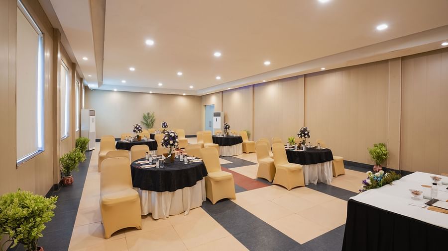 Well-lit meeting area with tables set with a flower bouquet at Shri Radha Brij Vasundhara Resort & Spa, Mathura