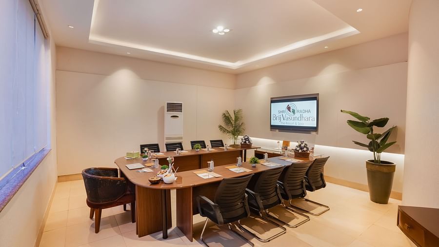 Well-lit conference room with a projector screen and comfortable seating at Shri Radha Brij Vasundhara Resort & Spa, Mathura