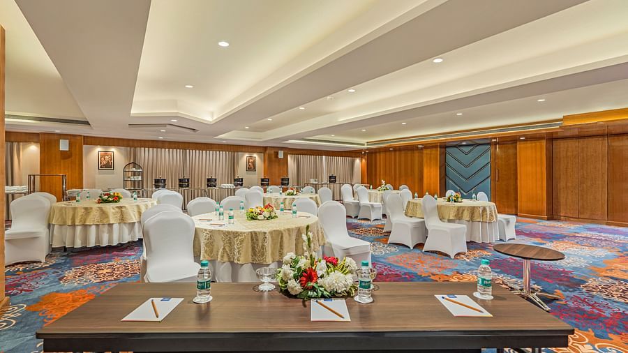 Round seating arrangements at Euphorbia hall with a table having pen and paper on it - Shyama Sarovar Portico Orai