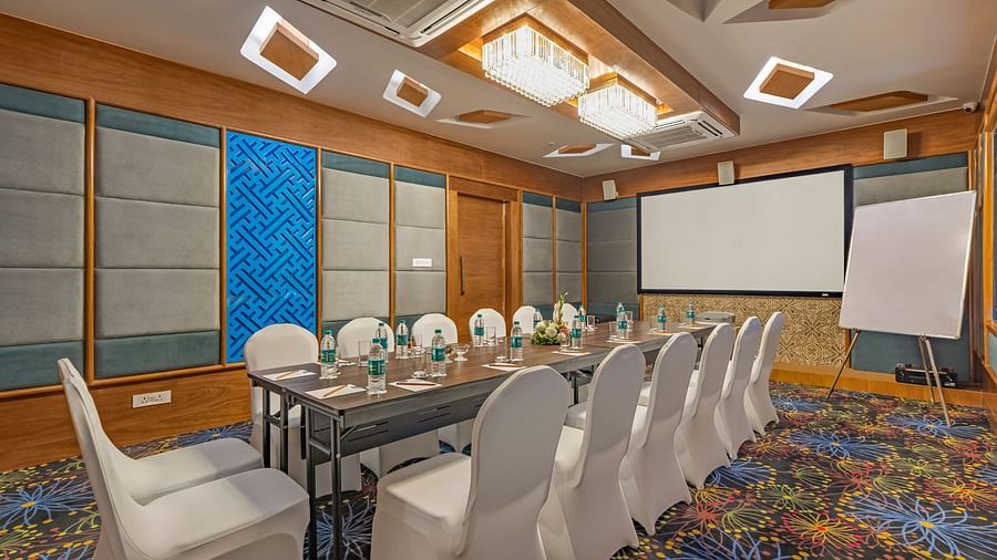 Seating arrangements inside the meeting hall with a projector screen - Shyama Sarovar Portico Orai