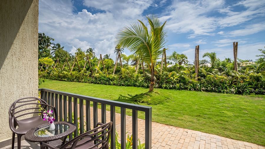 image of the balcony at the premium cottage opening to a lush green lawn on a sunny day with seating area on the porch
