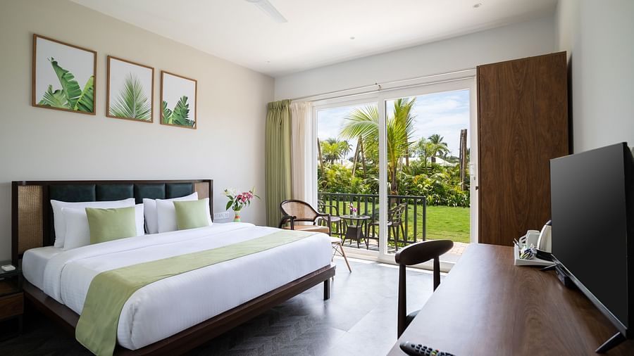 full view image of the premium cottage at sibaya beach resort in morjim beac, goa featuring a lush green scenic view from the huge windows in the room