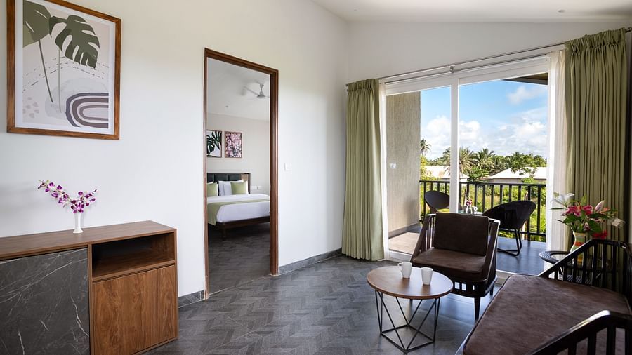 image of the living room from a corner with a door leading inside the bedroom along with huge french windows