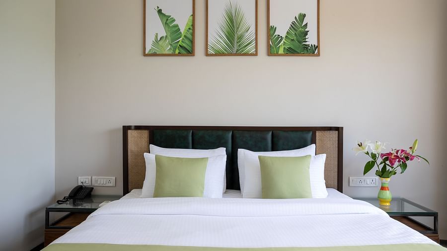 front view of the queen size bed with three illustrations wall mounted above it at the garden suite