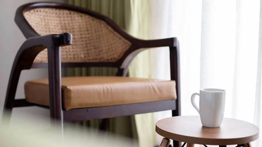 close up image of an arm chair along with a coffee table with a white mug kept on it at the garden suite