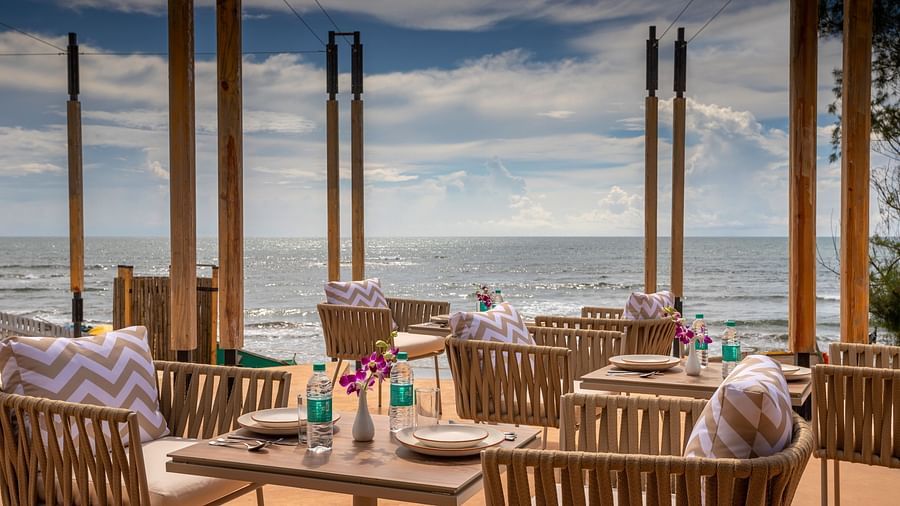 image of well arranged tables and chairs at saz on the beach restaurant with sea waves crashing on the beach in the background